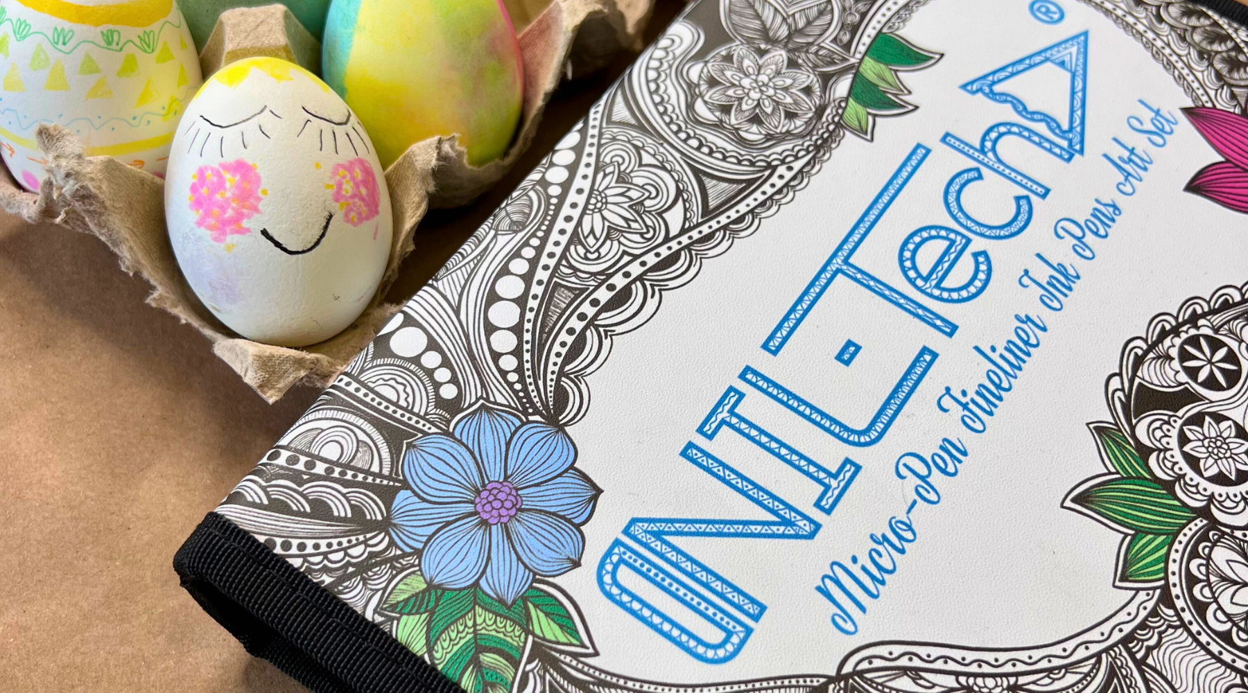 Colorful tie-dye Easter eggs decorated with intricate doodles using brush pens on a crafting table